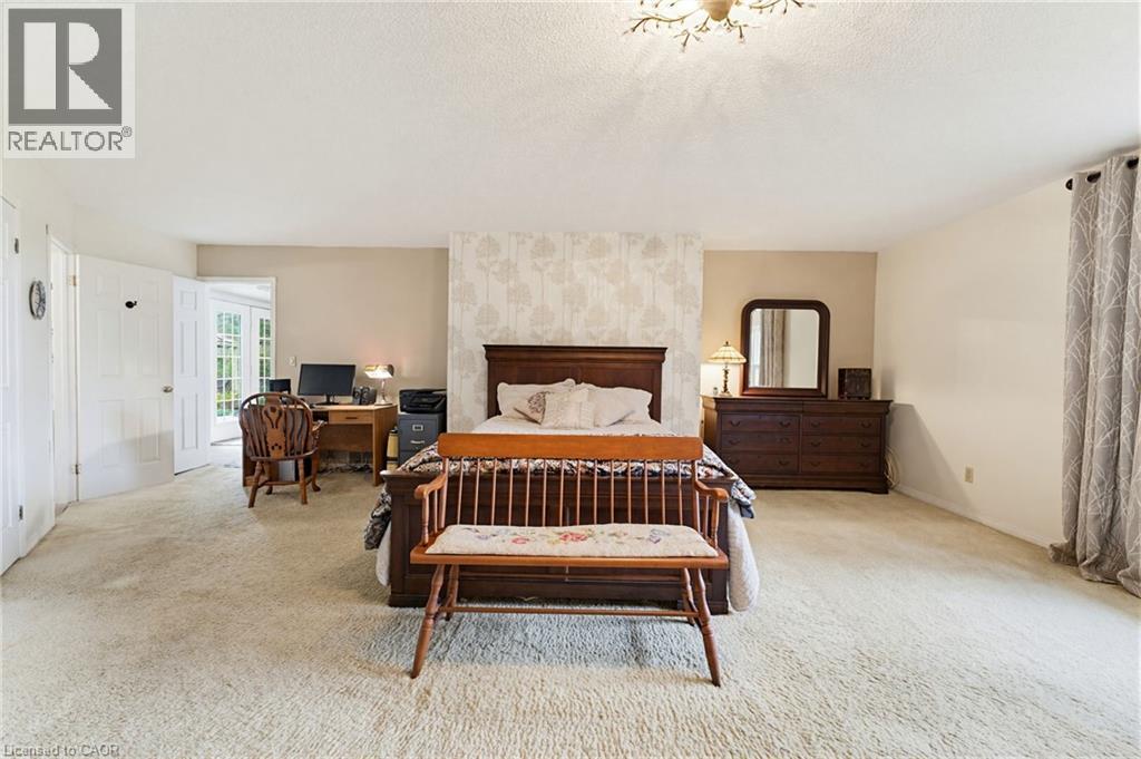 Spacious room featuring neutral carpet flooring, light-toned wall paint, and a decorative ceiling light fixture - 10 Huisman Lane, Hamilton, ON