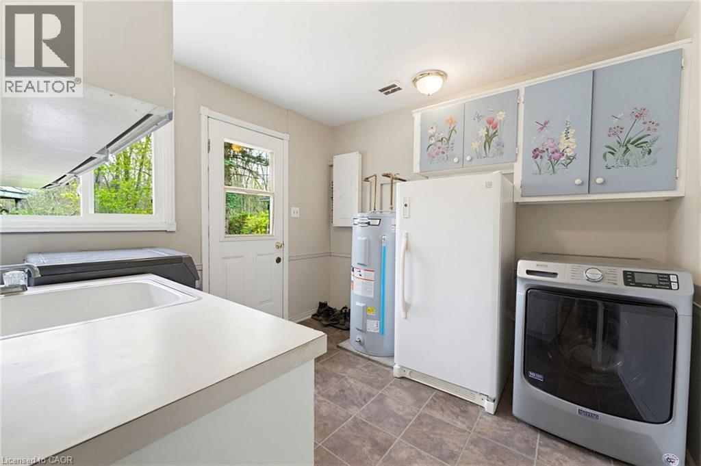 Utility room with a white drop-in sink, durable countertop space, and tiled flooring - 10 Huisman Lane, Hamilton, ON
