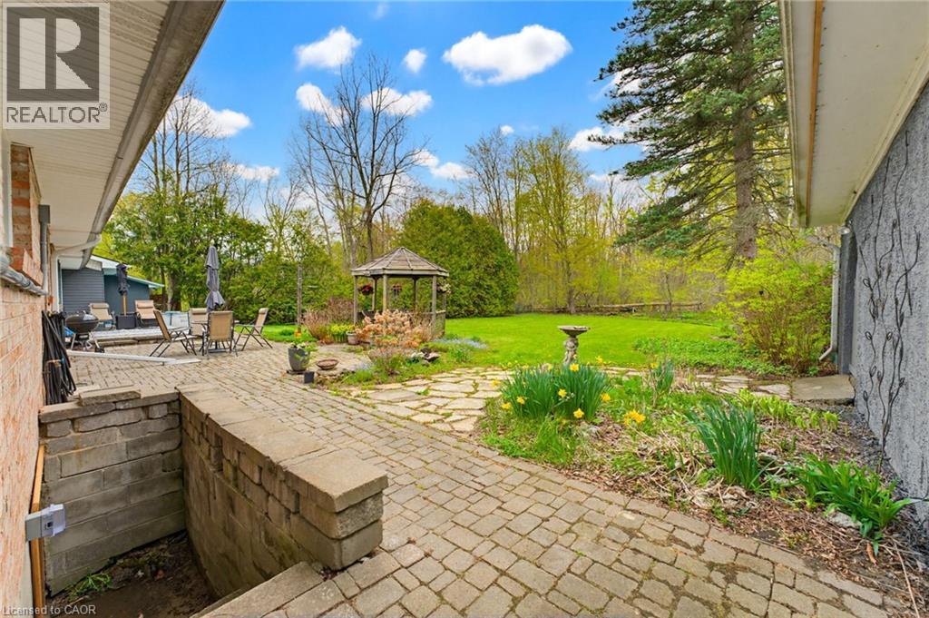 Expansive outdoor living area featuring a large paver patio, a stone path, a built-in stone retaining wall, and a wood gazebo - 10 Huisman Lane, Hamilton, ON