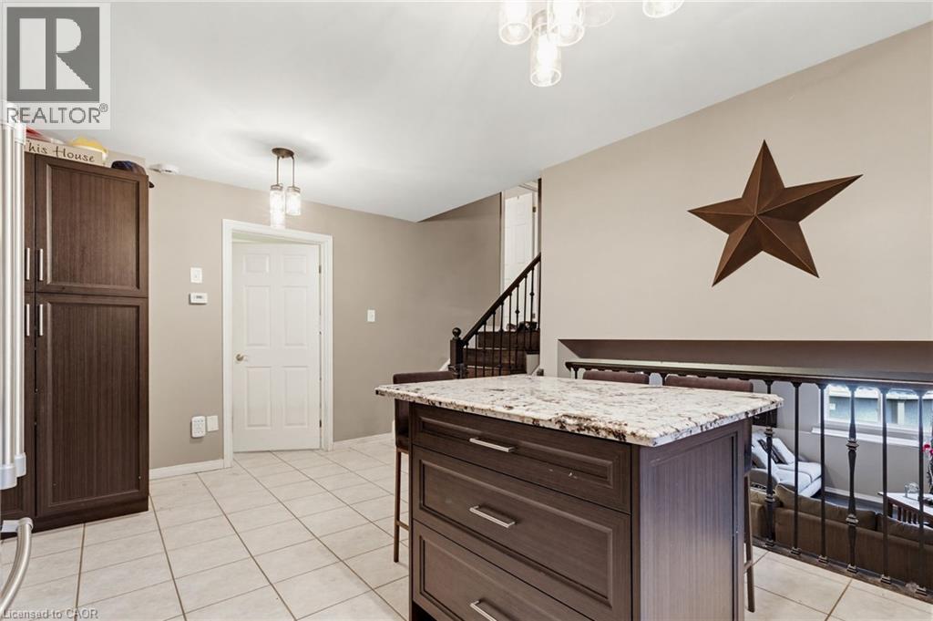 Kitchen island with a granite countertop and dark wood-finish cabinetry - 47 Hannah Crescent, Hamilton, ON - Indoor Photo Showing Other Room