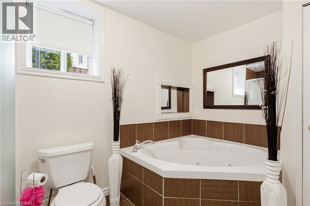 Corner jetted tub featuring a tiled surround and chrome fixtures - 47 Hannah Crescent, Hamilton, ON - Indoor Photo Showing Bathroom