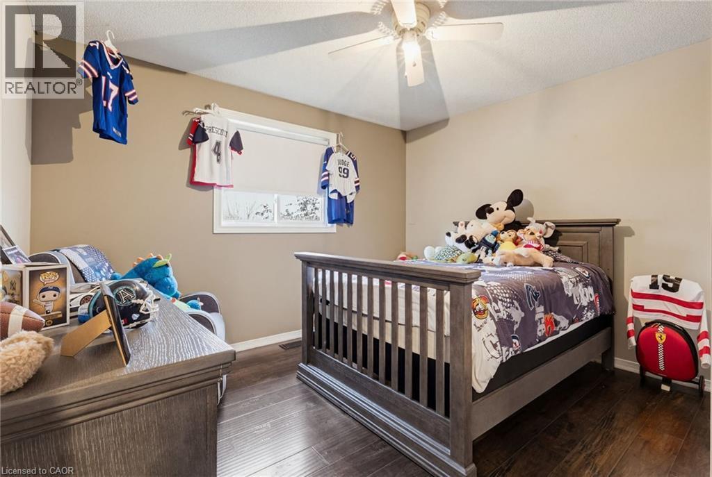 Bedroom featuring wood-finish flooring, a window with roller blinds, a ceiling fan with integrated lighting, and neutral wall tones - 47 Hannah Crescent, Hamilton, ON - Indoor Photo Showing Bedroom