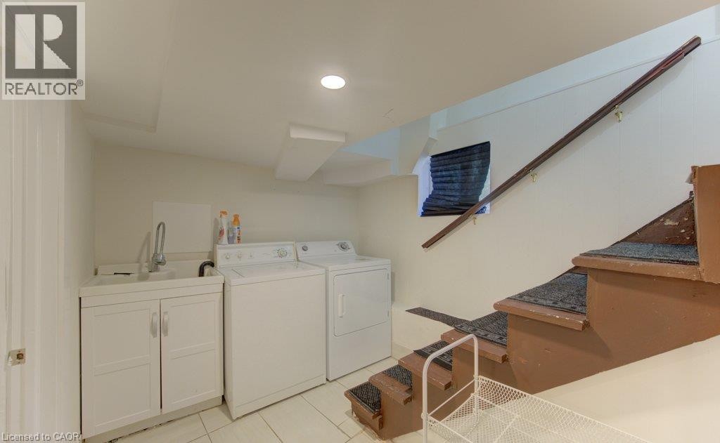 Laundry area featuring a utility sink, cabinet storage, tile flooring, and integrated lighting - 10 Marshall Street, Waterloo, ON