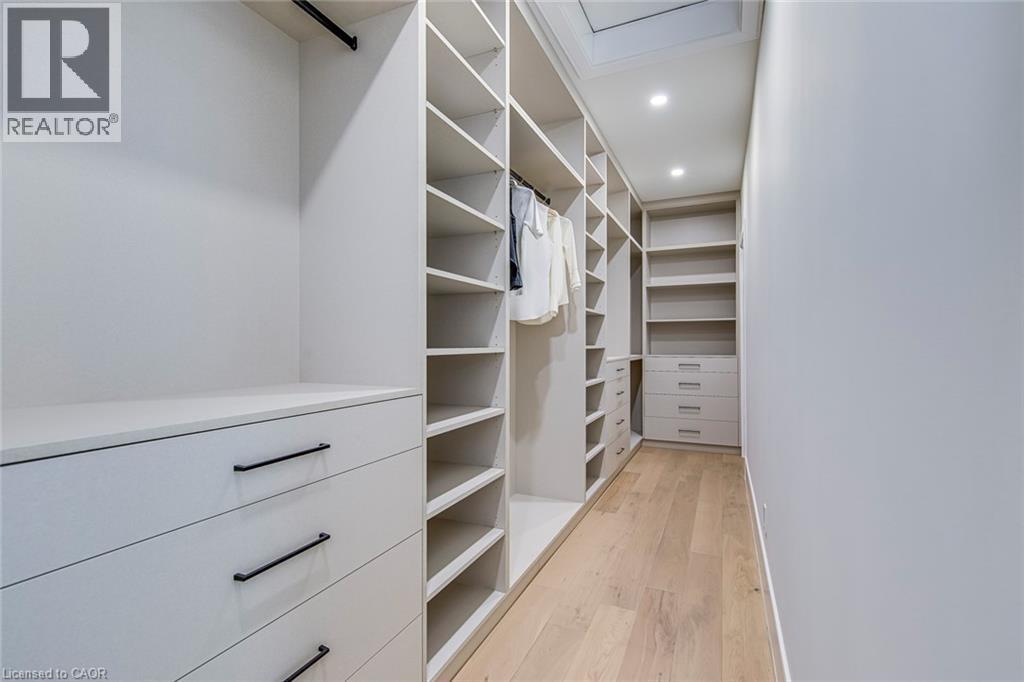 Custom closet system featuring extensive shelving, built-in drawers with black bar pull hardware, and dedicated hanging rods - 1411 Mountain Grove Avenue, Burlington, ON - Indoor