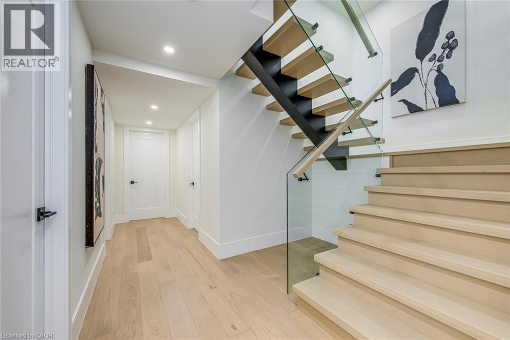 Modern staircase featuring light wood treads, a glass railing, and a black steel stringer - 1411 Mountain Grove Avenue, Burlington, ON - Indoor Photo Showing Other Room