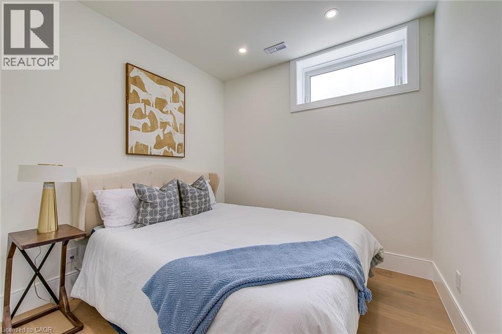 Light wood-finish flooring with white baseboards, recessed lighting, and a horizontal window with white trim - 1411 Mountain Grove Avenue, Burlington, ON - Indoor Photo Showing Bedroom