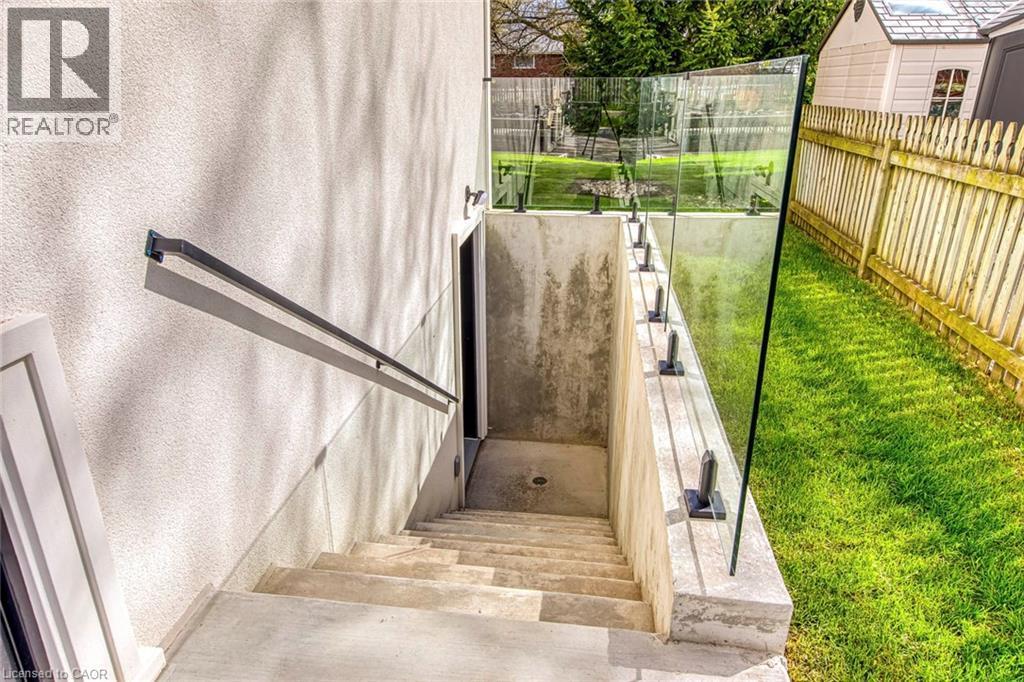 Exterior concrete staircase with a dark metal handrail, enclosed by a glass panel railing system - 1411 Mountain Grove Avenue, Burlington, ON - Outdoor With Exterior
