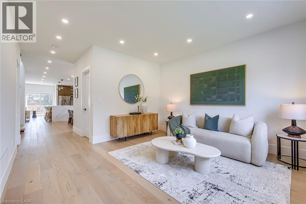 Open-concept living space featuring light wood-finish flooring, recessed lighting, white walls, and a visible kitchen beyond - 1411 Mountain Grove Avenue, Burlington, ON - Indoor Photo Showing Living Room