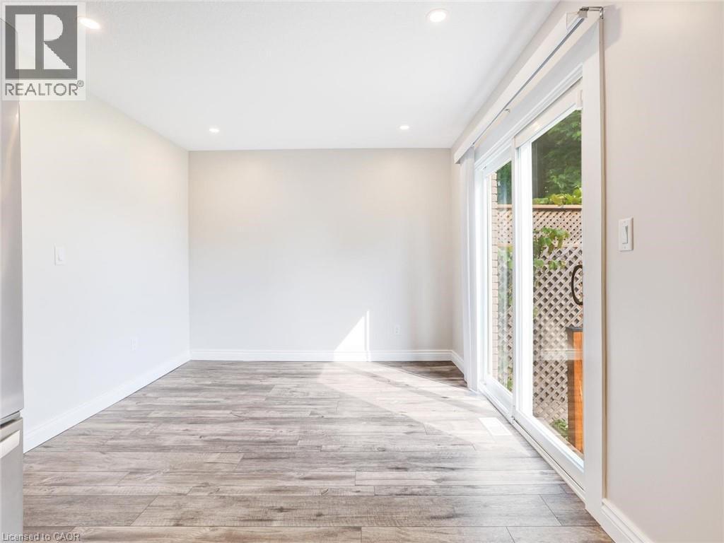 Spacious interior with wood-finish flooring, recessed lighting, white baseboards, and a large sliding glass door opening to outdoor lattice - 833 Doon Village Road, Kitchener, ON - Indoor Photo Showing Other Room