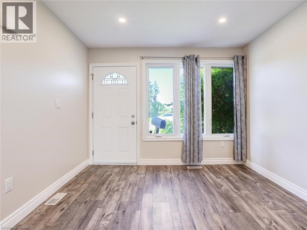 Entryway featuring wood-finish flooring, a white paneled door with arched transom, two large windows, white baseboards, and recessed lighting - 833 Doon Village Road, Kitchener, ON - Indoor Photo Showing Other Room