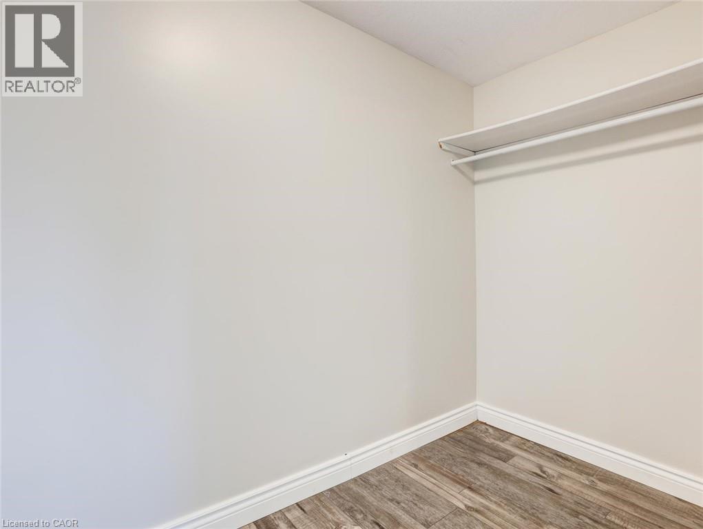 Interior closet space featuring white walls and wood-finish flooring - 833 Doon Village Road, Kitchener, ON - Indoor