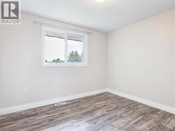 Room featuring wood-finish flooring, white baseboards, and neutral wall tones -