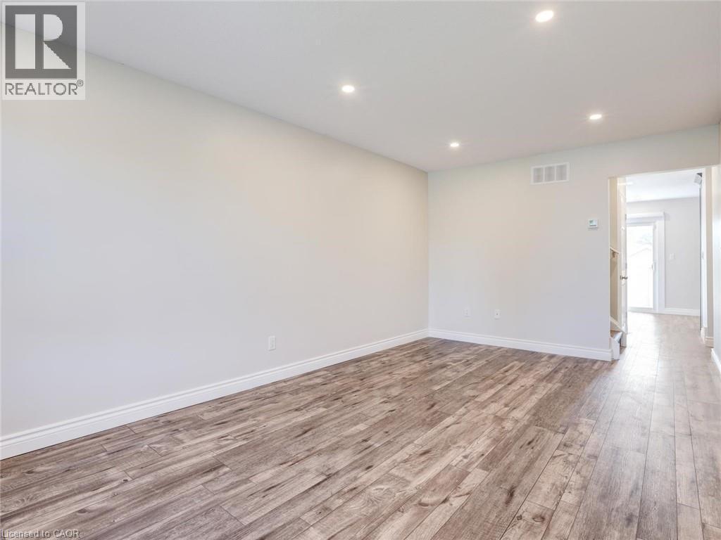Spacious room with wood-finish flooring, recessed lighting, white baseboards, and neutral wall tones - 833 Doon Village Road, Kitchener, ON - Indoor Photo Showing Other Room