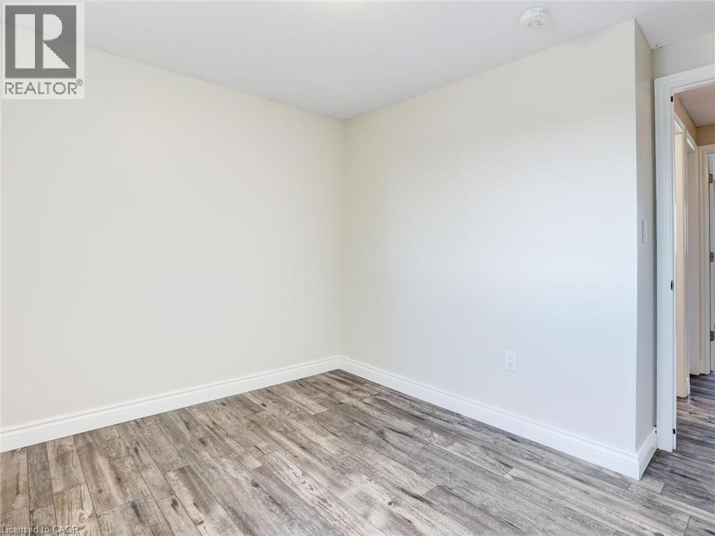 Neutral painted walls with wood-finish flooring and white baseboards - 833 Doon Village Road, Kitchener, ON - Indoor Photo Showing Other Room