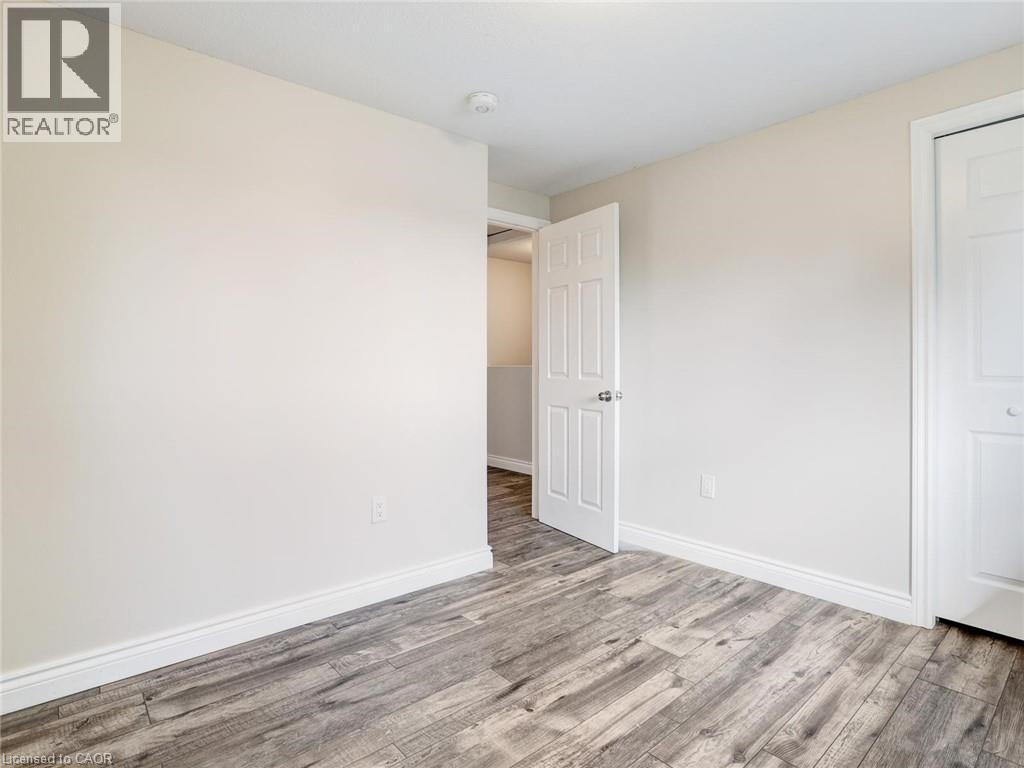 Room featuring wood-finish flooring, light-toned walls, white trim, and a white paneled door - 833 Doon Village Road, Kitchener, ON - Indoor Photo Showing Other Room