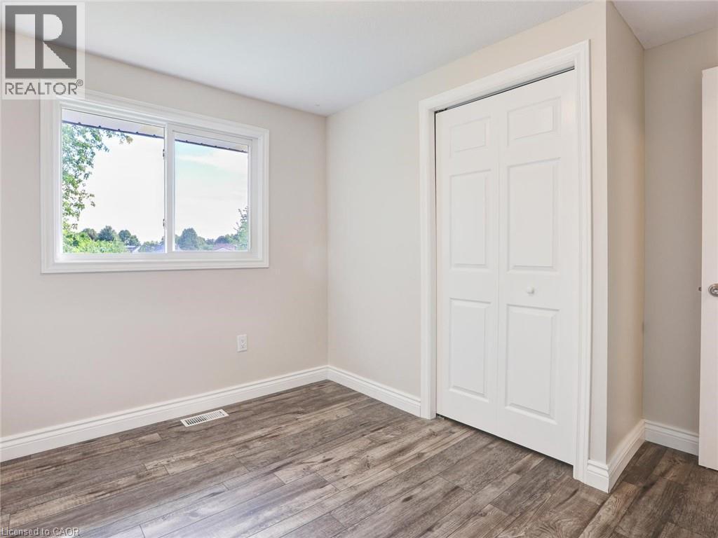 Light-filled room featuring wood-finish flooring, a white-framed window, and bi-fold closet doors - 833 Doon Village Road, Kitchener, ON - Indoor Photo Showing Other Room