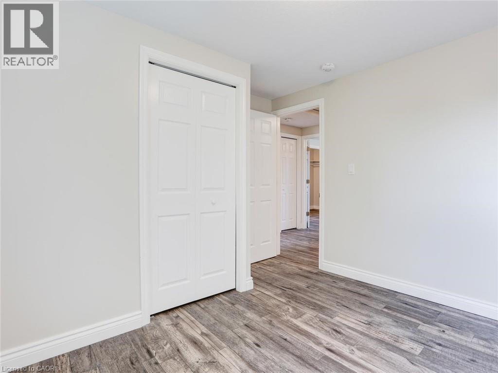 Room featuring wood-finish flooring, light-toned walls, white baseboards, and a white bi-fold closet door - 833 Doon Village Road, Kitchener, ON - Indoor Photo Showing Other Room