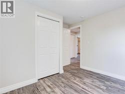 Room featuring wood-finish flooring, light-toned walls, white baseboards, and a white bi-fold closet door -