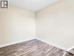 Interior room featuring light-toned walls, wood-finish flooring, and crisp white baseboards -