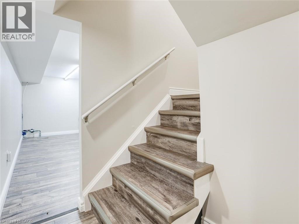 Staircase with wood-finish treads and risers, featuring a white handrail and light neutral wall paint - 833 Doon Village Road, Kitchener, ON - Indoor Photo Showing Other Room
