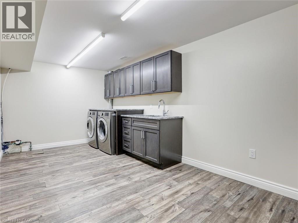 Laundry area featuring wood-finish flooring, white walls, and built-in cabinetry - 833 Doon Village Road, Kitchener, ON - Indoor Photo Showing Laundry Room