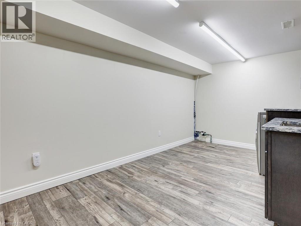 Spacious room featuring wood-finish flooring, white baseboards, and neutral wall tones - 833 Doon Village Road, Kitchener, ON - Indoor
