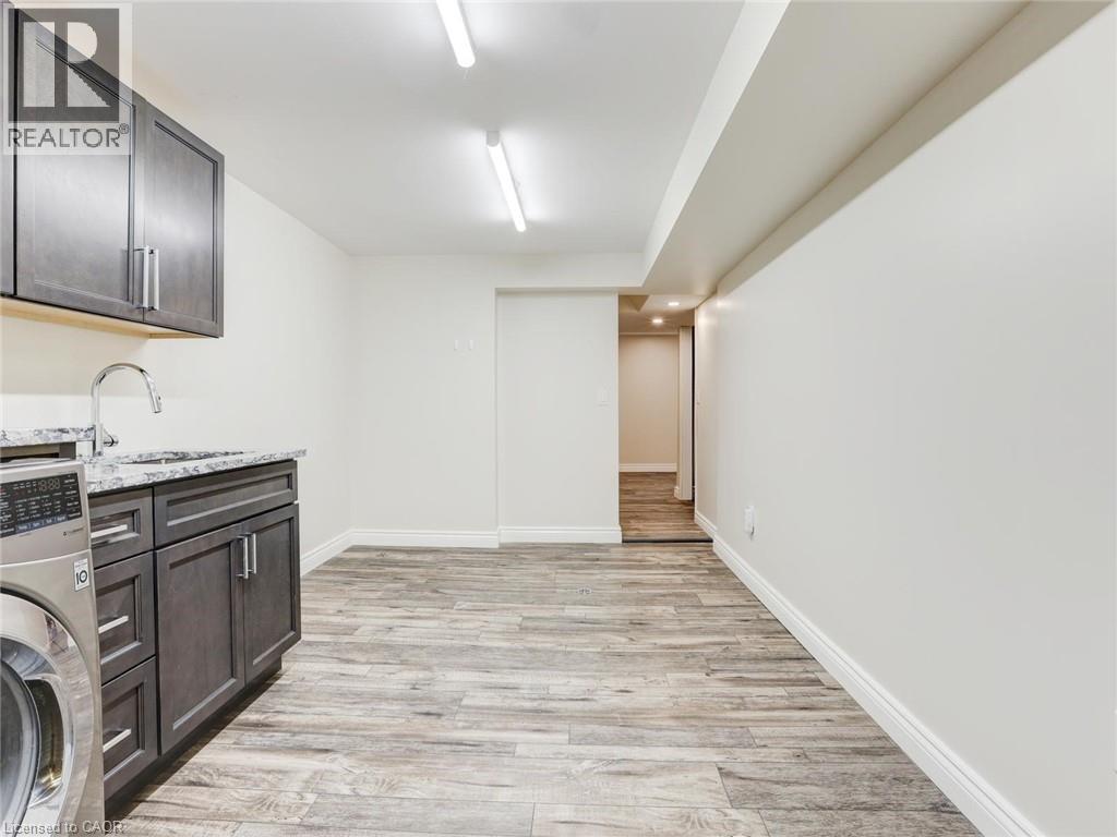 Utility room featuring wood-finish flooring, white baseboards, and bright overhead lighting - 833 Doon Village Road, Kitchener, ON - Indoor