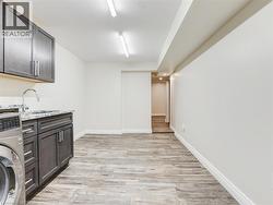 Utility room featuring wood-finish flooring, white baseboards, and bright overhead lighting -