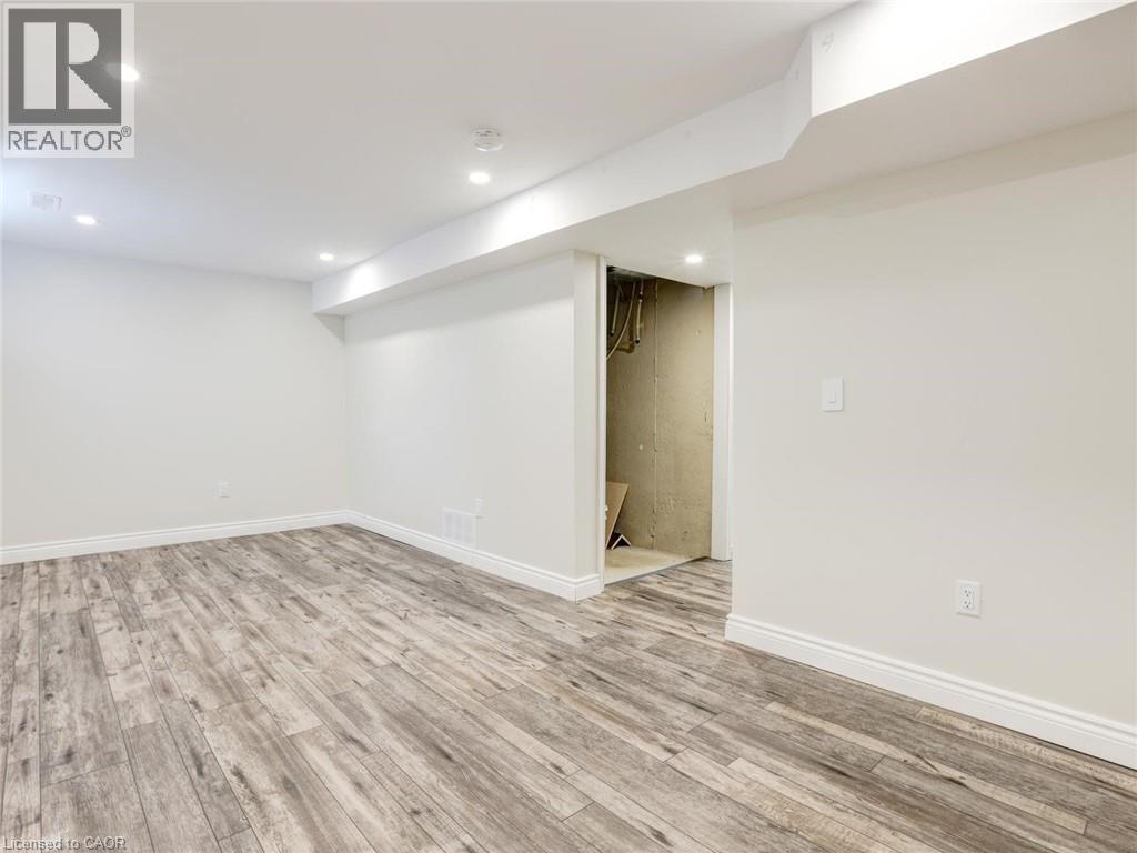 Spacious room featuring wood-finish flooring, white baseboards, recessed lighting, and crisp white walls - 833 Doon Village Road, Kitchener, ON - Indoor Photo Showing Other Room