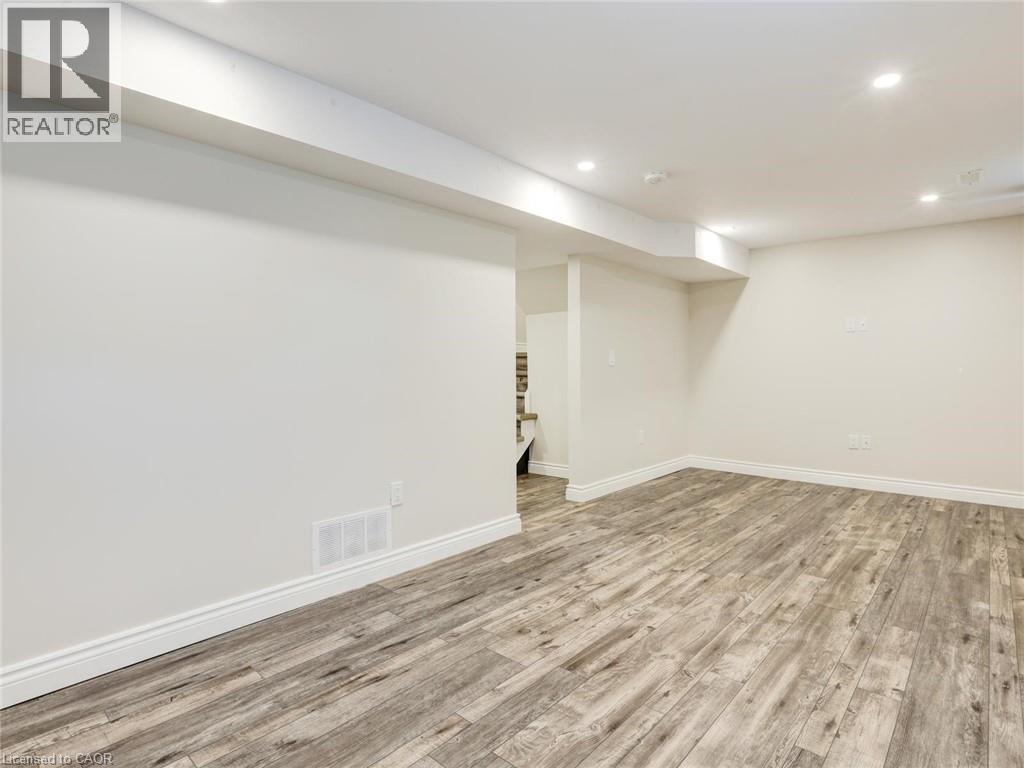 Finished lower level space featuring wood-finish flooring, recessed lighting, white baseboards, and neutral wall paint - 833 Doon Village Road, Kitchener, ON - Indoor