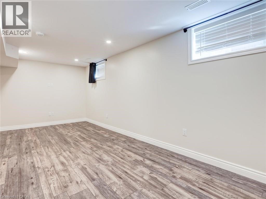Spacious room featuring wood-finish flooring, recessed lighting, and a window with horizontal blinds - 833 Doon Village Road, Kitchener, ON - Indoor