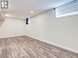 Spacious room featuring wood-finish flooring, recessed lighting, and a window with horizontal blinds -