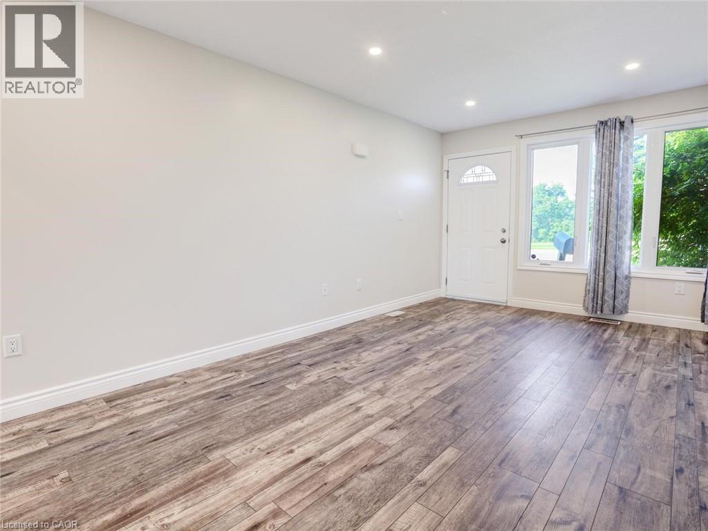 Spacious interior featuring wood-finish flooring, recessed lighting, and a white entry door with decorative glass - 833 Doon Village Road, Kitchener, ON - Indoor Photo Showing Other Room