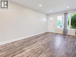 Spacious interior featuring wood-finish flooring, recessed lighting, and a white entry door with decorative glass -