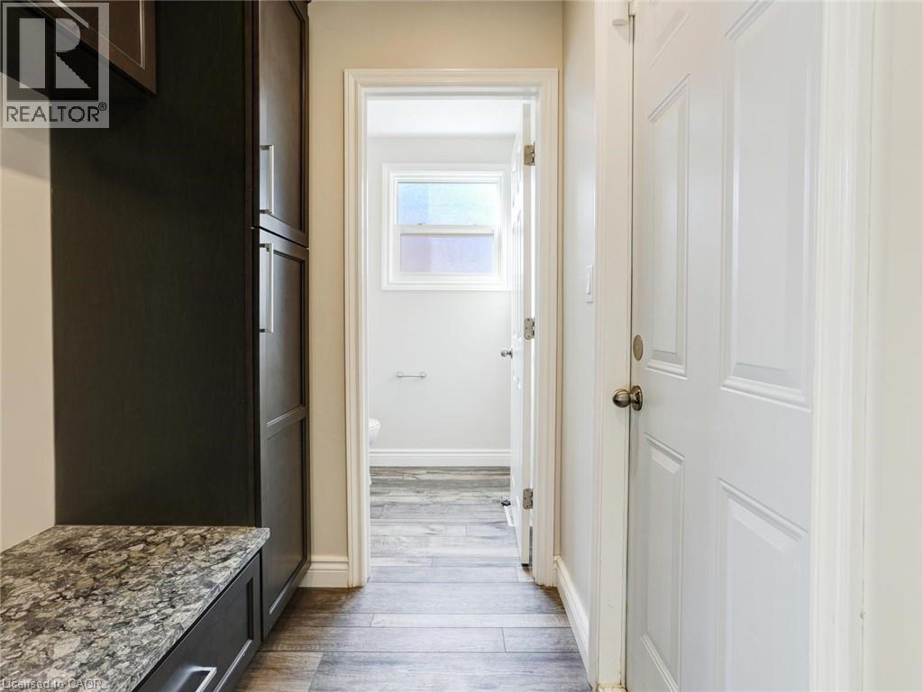 Hallway featuring wood-finish flooring, a white paneled door, and built-in cabinetry with a stone-finish countertop - 833 Doon Village Road, Kitchener, ON - Indoor Photo Showing Other Room