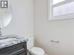 Bathroom featuring a dark wood-finish vanity with an integrated sink, patterned countertop, and a circular wall mirror -