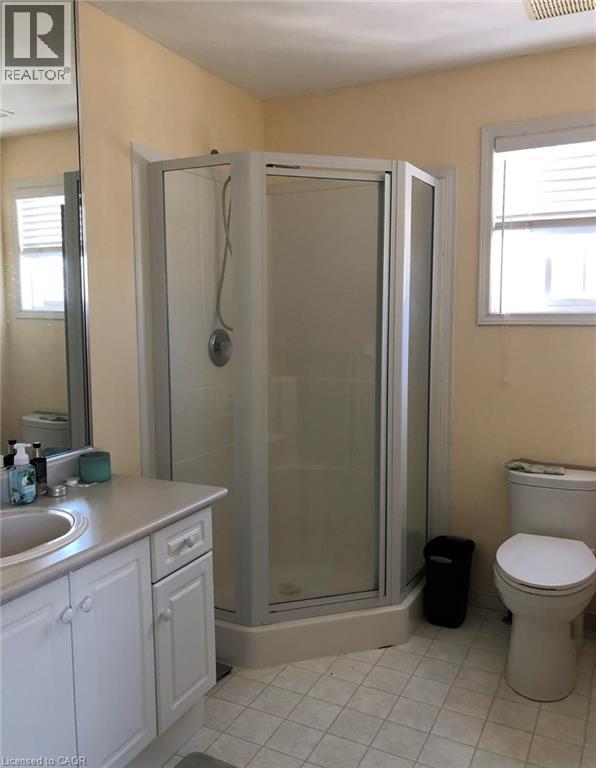 Bathroom featuring a corner glass-enclosed shower, white vanity with integrated sink, light-toned countertop, and a toilet - 350 Havendale Crescent, Waterloo, ON - Indoor Photo Showing Bathroom