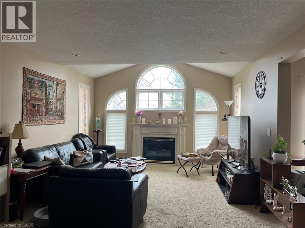 Living area featuring vaulted ceilings, a central fireplace with a mantel, and decorative arched windows - 350 Havendale Crescent, Waterloo, ON - Indoor Photo Showing Living Room With Fireplace