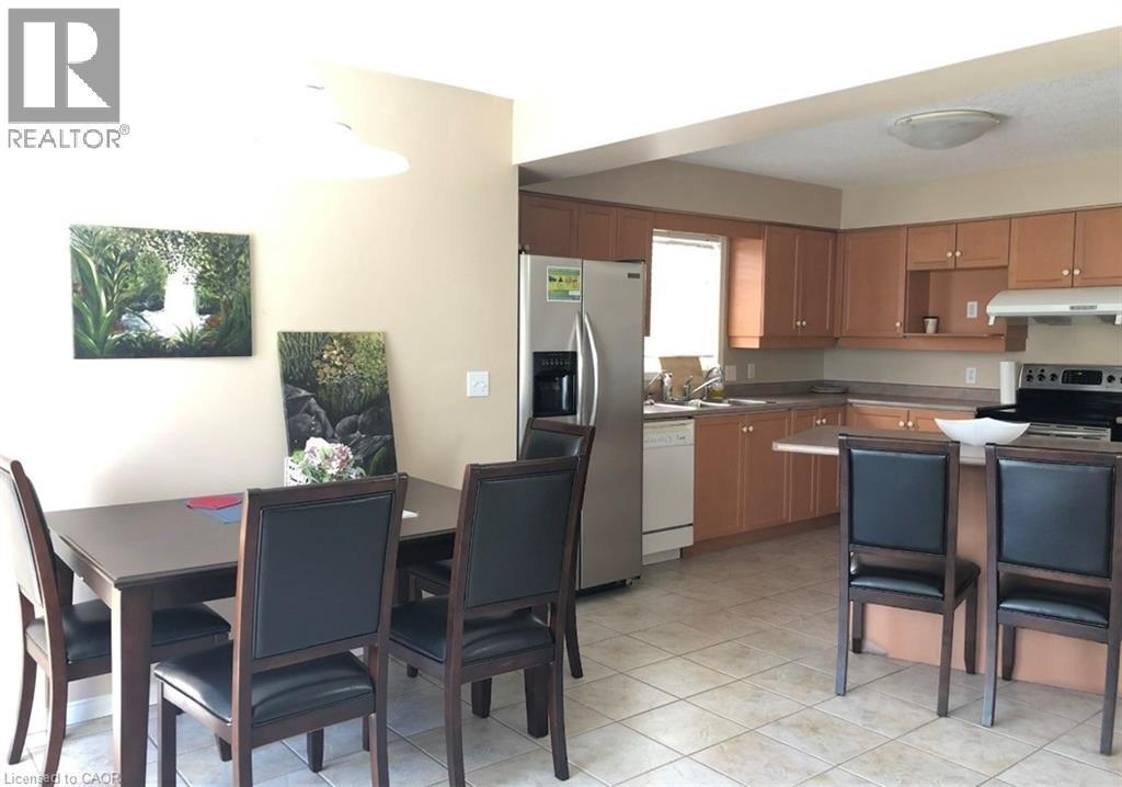 Open-concept kitchen and dining area featuring light-toned cabinetry, stainless steel appliances, and a breakfast bar - 350 Havendale Crescent, Waterloo, ON - Indoor