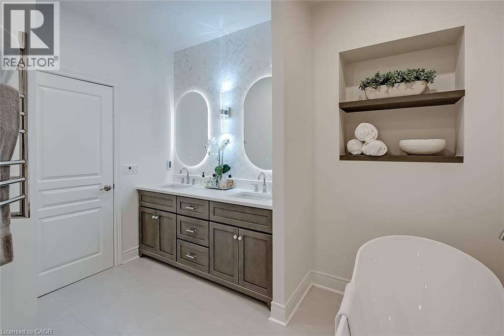 Contemporary bathroom featuring a freestanding tub, recessed shelving with wood-finish inserts, and a double vanity with stone countertops - 4285 Couples Crescent, Burlington, ON - Indoor Photo Showing Bathroom
