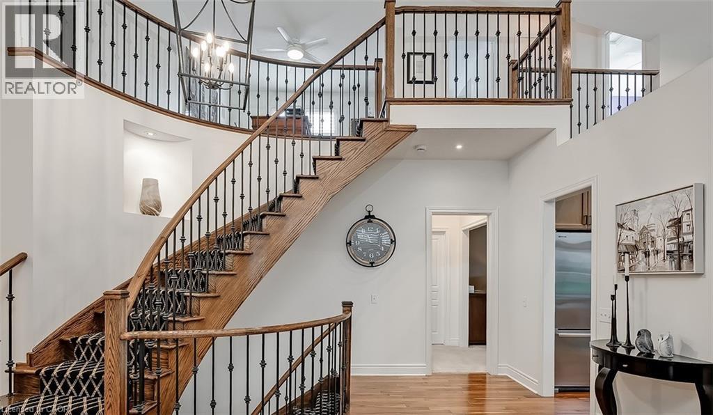 Grand curved staircase featuring wood treads, wrought iron balusters, and a patterned runner - 4285 Couples Crescent, Burlington, ON - Indoor Photo Showing Other Room