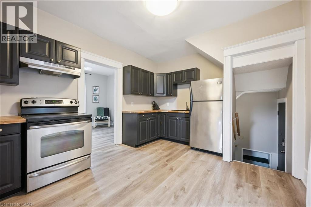 Kitchen featuring dark cabinetry, stainless steel appliances, wood-finish countertops, and light wood-finish flooring - 15 Gordon Avenue, Kitchener, ON - Indoor Photo Showing Kitchen