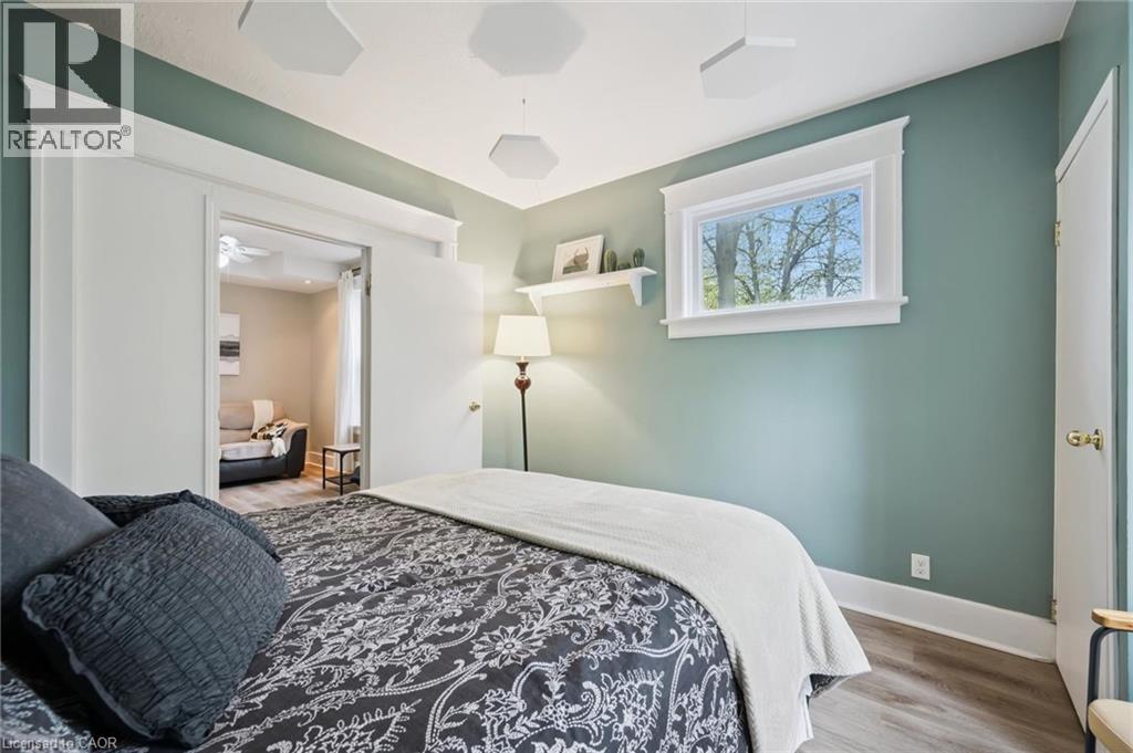 Bedroom featuring light wood-finish flooring, a window with white trim, and a doorway opening to an additional room - 15 Gordon Avenue, Kitchener, ON - Indoor Photo Showing Bedroom