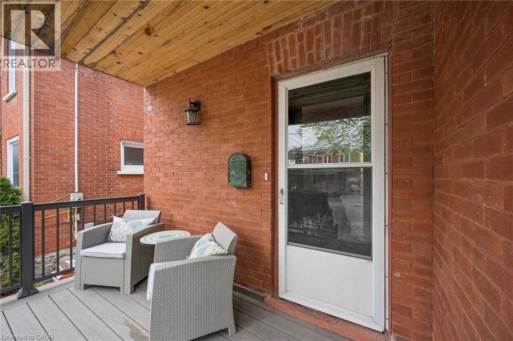 Front porch featuring a durable composite deck, black metal railing, and a wood-paneled ceiling - 15 Gordon Avenue, Kitchener, ON - Outdoor With Deck Patio Veranda With Exterior