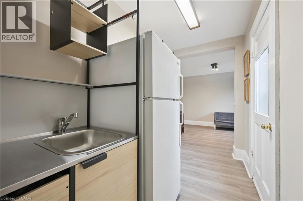 Compact kitchenette featuring a stainless steel sink, wood-finish cabinetry, and open shelving - 15 Gordon Avenue, Kitchener, ON - Indoor
