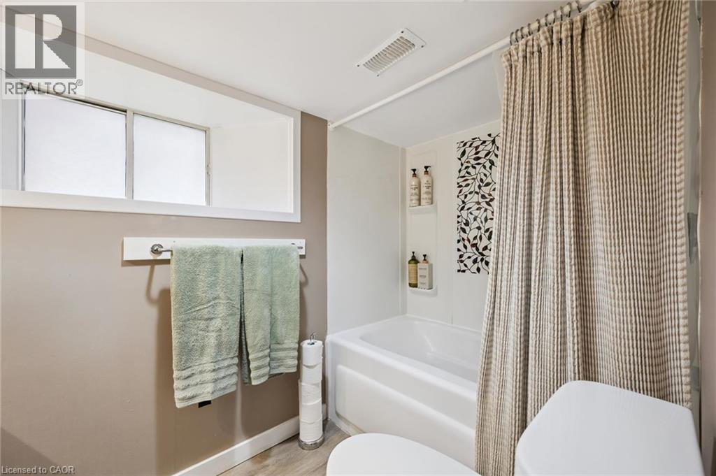 Bathroom featuring a white bathtub, decorative accent tile, and a privacy window - 15 Gordon Avenue, Kitchener, ON - Indoor Photo Showing Bathroom