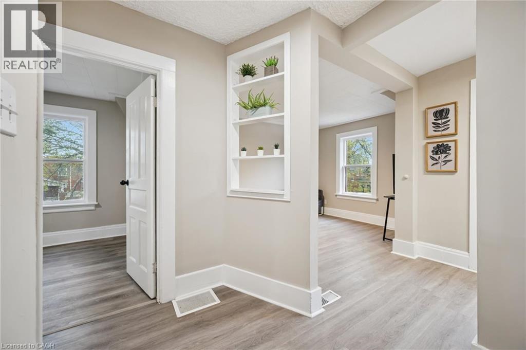 Light wood-finish flooring throughout, featuring a built-in shelving unit, white trim, and a paneled interior door - 15 Gordon Avenue, Kitchener, ON - Indoor Photo Showing Other Room