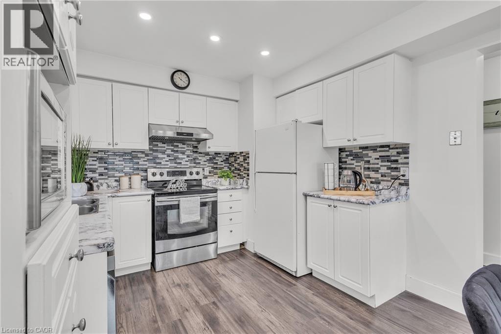 Kitchen featuring white cabinetry, wood-finish flooring, marbled countertops, a mosaic tile backsplash, and recessed lighting - 425 Erinbrook Drive, Kitchener, ON - Indoor Photo Showing Kitchen With Upgraded Kitchen
