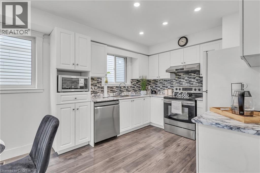 Modern kitchen featuring white shaker cabinetry, stainless steel appliances, and wood-finish flooring - 425 Erinbrook Drive, Kitchener, ON - Indoor Photo Showing Kitchen With Upgraded Kitchen