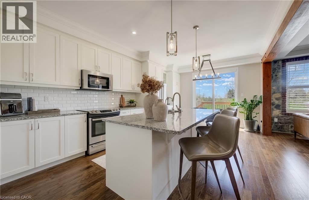 Kitchen island with a granite-style countertop and pendant lighting - 19 Shoreacres Drive, Kitchener, ON - Indoor Photo Showing Kitchen With Stainless Steel Kitchen With Upgraded Kitchen